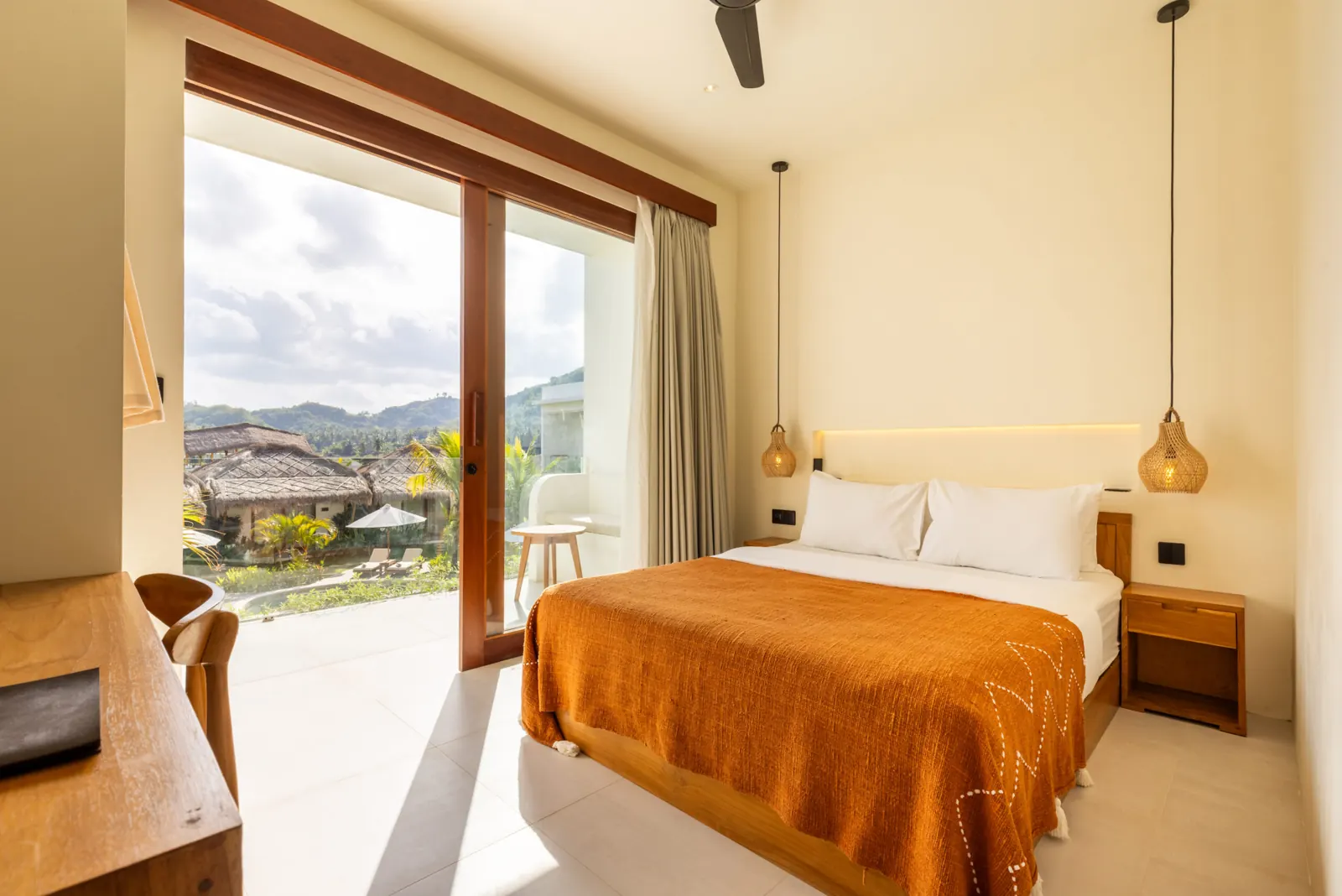 Double bed with glass doors opening onto a terrace with hill views