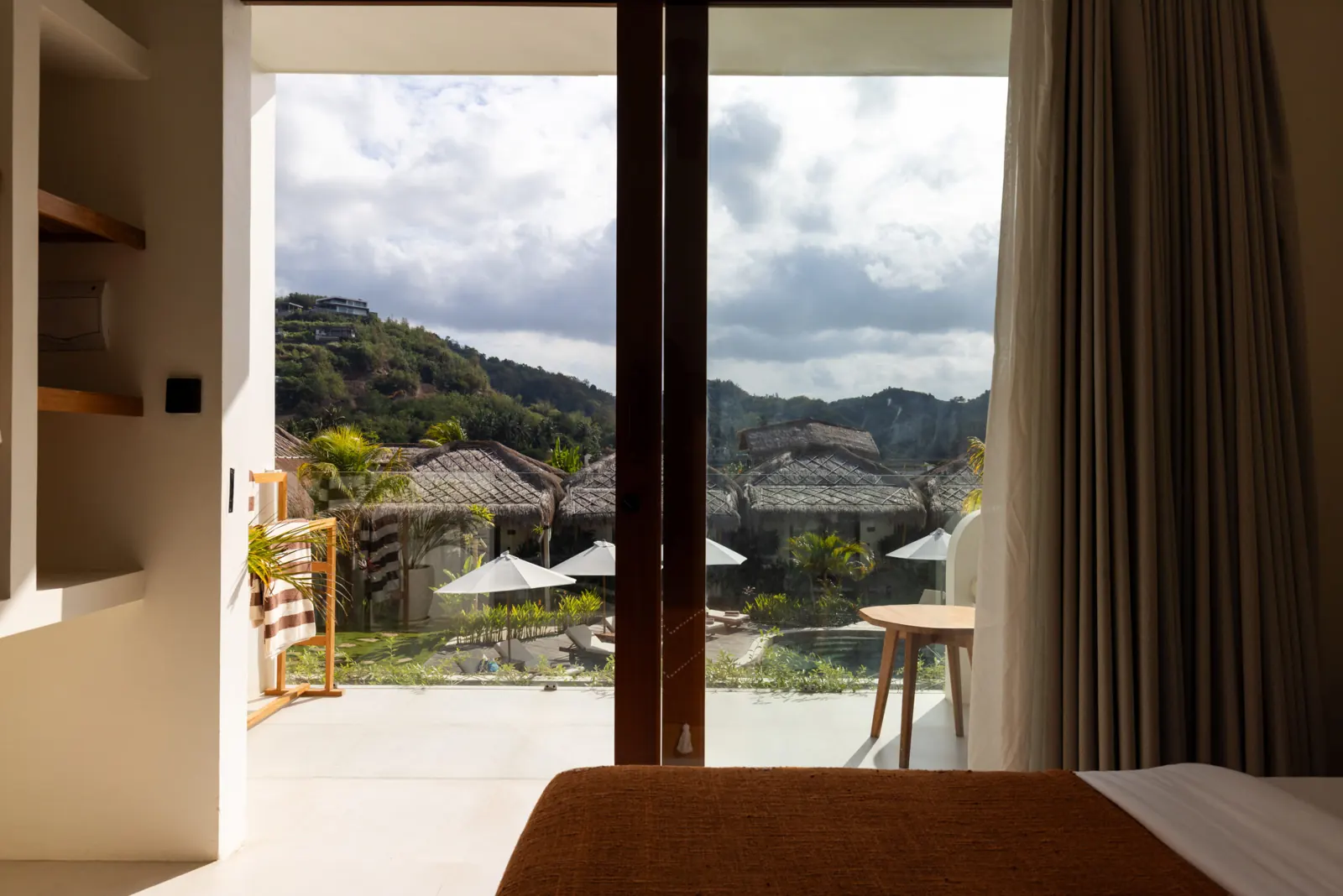View from the bed through open glass doors to the terrace and hills