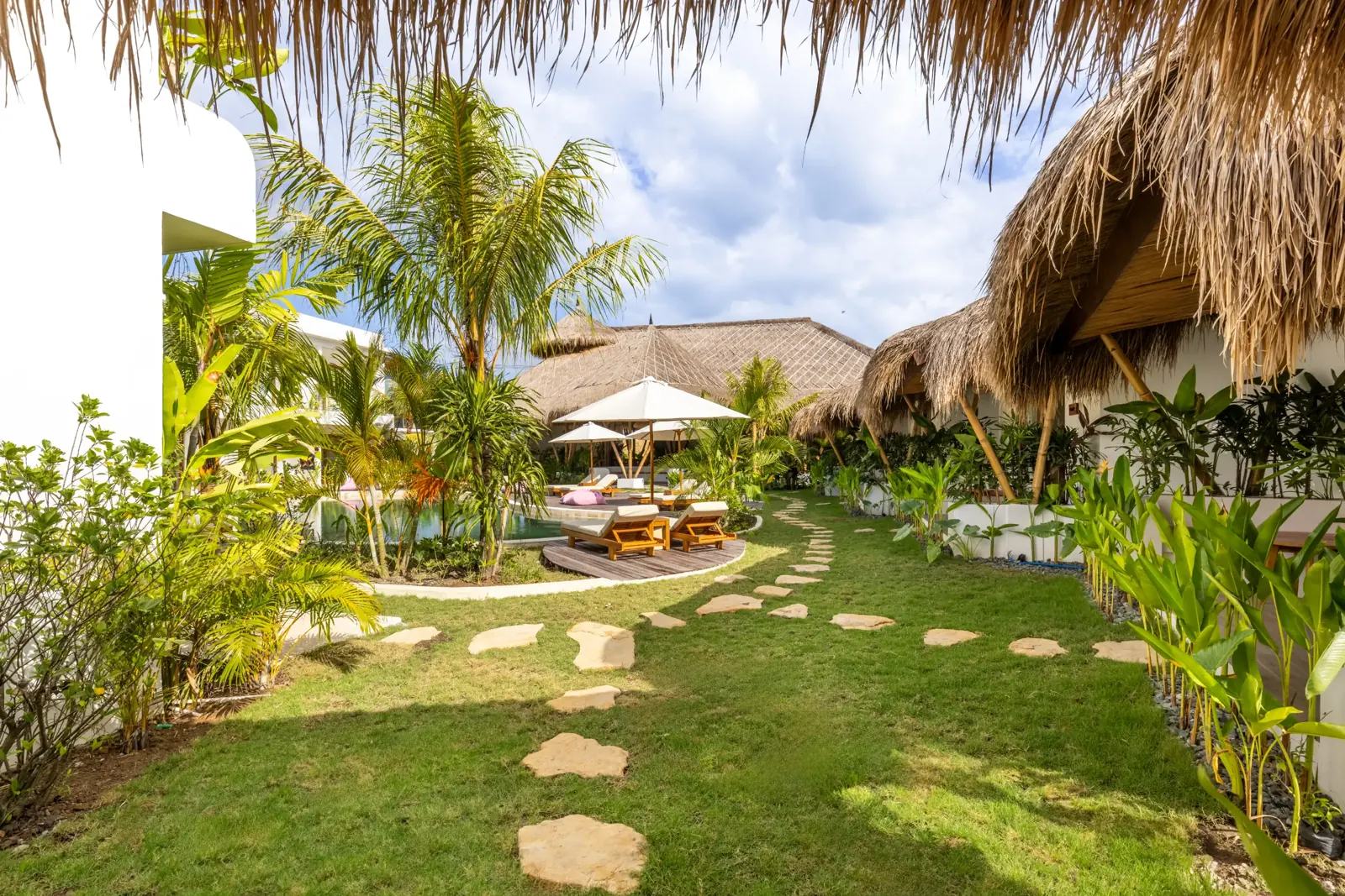 Bungalow garden with lawn, stepping stones and thatched roofs