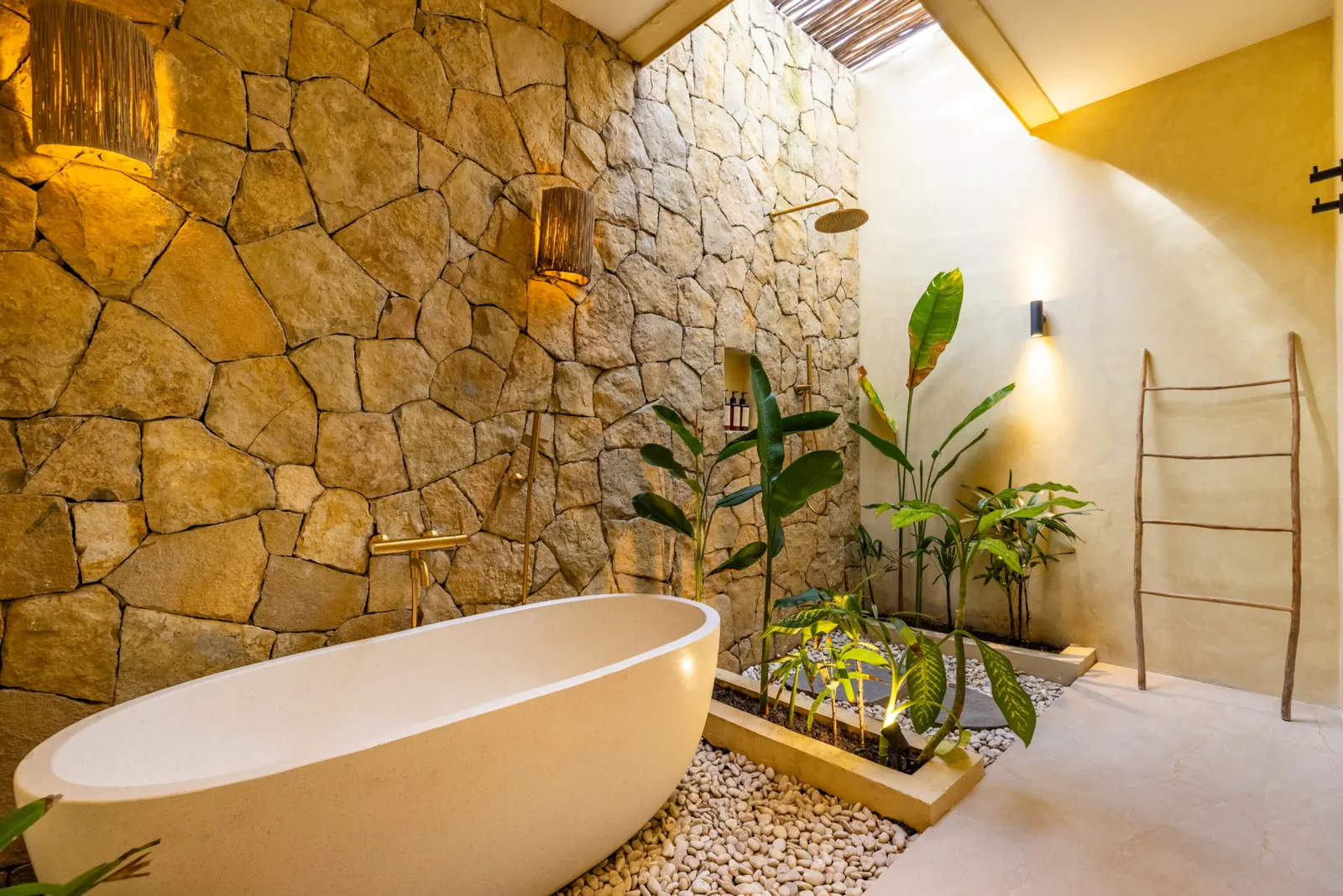 Bathroom with freestanding bathtub, stone wall and open-air planting